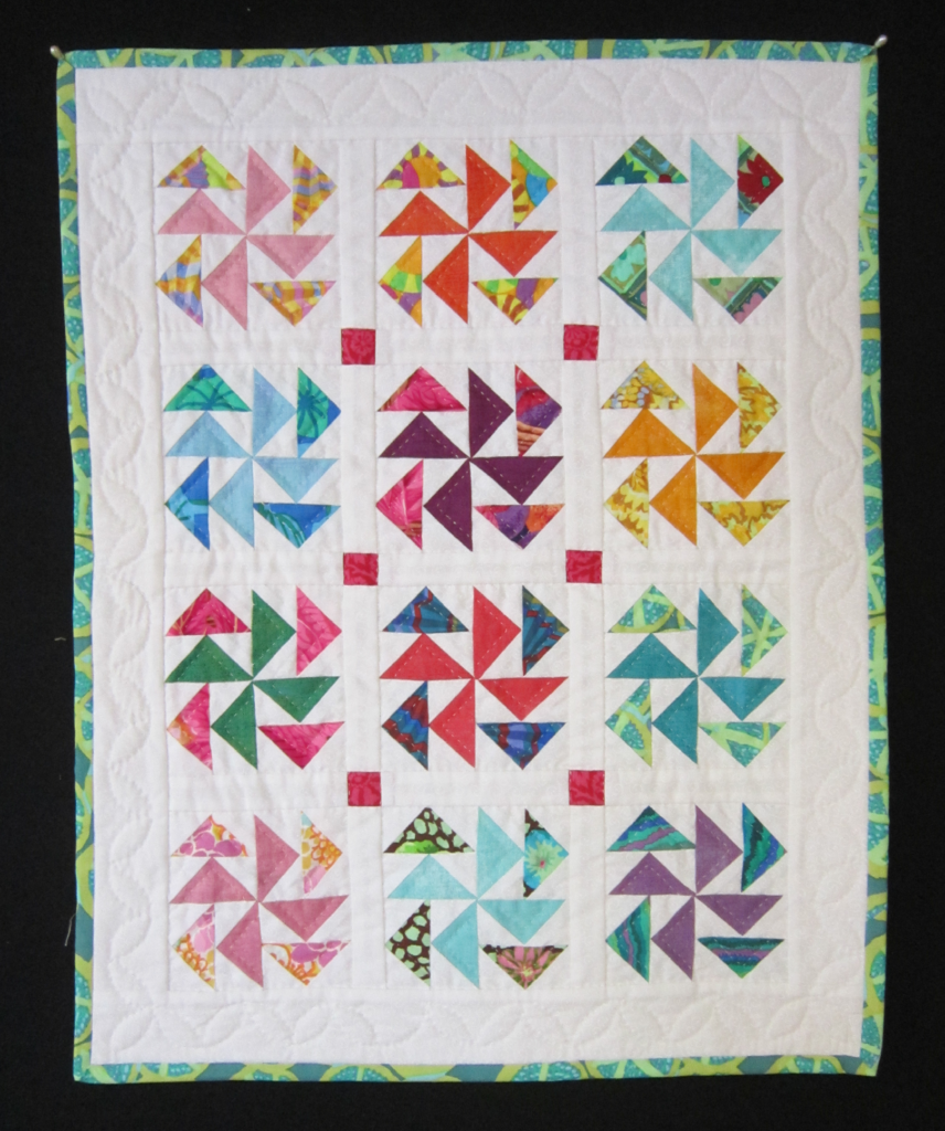 Flying Geese fan in rainbow colors set in four rows and three columns on a white background.